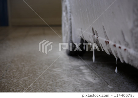 Foam flows from the car onto the white floor in the car wash. The car was treated with soap foam to clean off the dirt. The owner washes off dirt from the car wash. Foam flows from the car onto the white floor in the car wash. The car was treated with soap foam to clean off the dirt. The owner washes off dirt from the car wash. 114406783