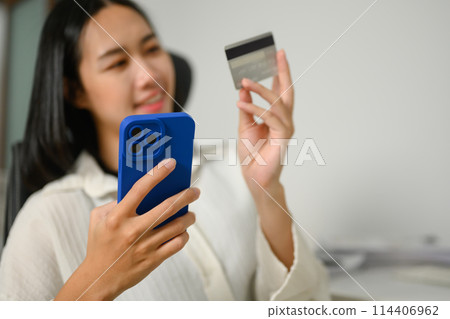 Happy young woman with credit card making internet order purchase on mobile phone 114406962