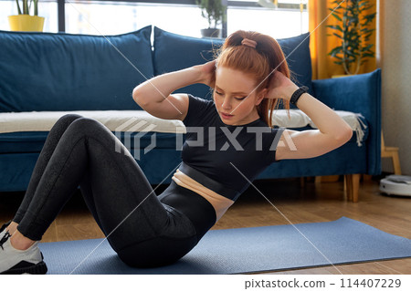 athlete attractive cool sporty woman doing fitness exercise on floor at home, alone 114407229