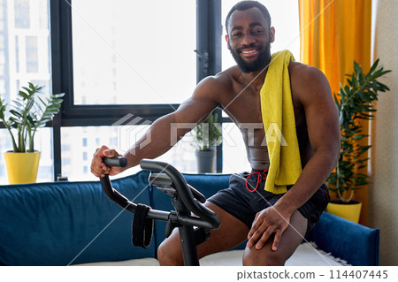 Indoor cycling, spinning cycling training. black man training on a stationary exercise bike Indoor cycling, spinning cycling training. black man training on a stationary exercise bike 114407445