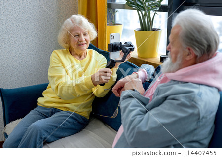 happy retired couple with smartphone making selfie, taking photo and video on smartphone 114407455