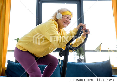 aged woman training and doing exercise on cycle at home. active pensioner lifestyle 114407565