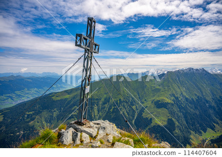A cross marks the summit of Pihapper Mountain against a backdrop of sweeping alpine vistas. Hohe Tauern, Austria A cross marks the summit of Pihapper Mountain against a backdrop of sweeping alpine vistas. Hohe Tauern, Austria 114407604