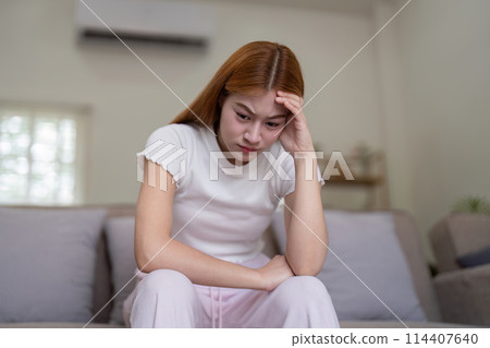 Woman asian frustrated ill sit sofa suffer headache migraine pain have health problem in house living room Woman asian frustrated ill sit sofa suffer headache migraine pain have health problem in house living room 114407640