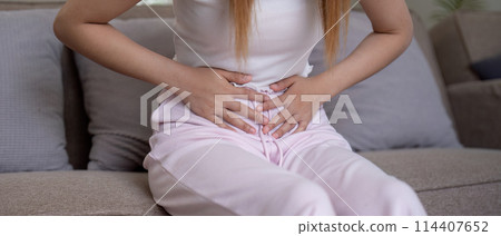 Young woman suffering from stomach ache on sofa at home Young woman suffering from stomach ache on sofa at home 114407652