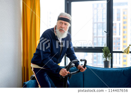 Senior person training on stationary bicycle doing physical exercise and activity. Senior person training on stationary bicycle doing physical exercise and activity. 114407656