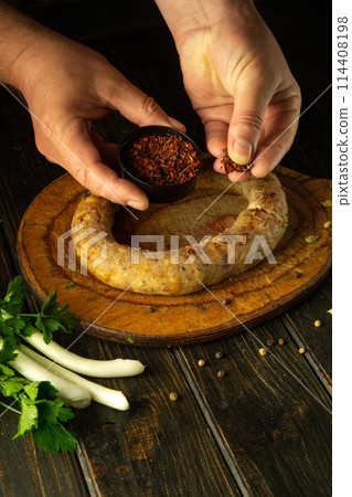 Men hands add aromatic spices to homemade sausage. The concept of preparing sausage at home for the holiday table. Advertising space Men hands add aromatic spices to homemade sausage. The concept of preparing sausage at home for the holiday table. Advertising space 114408198