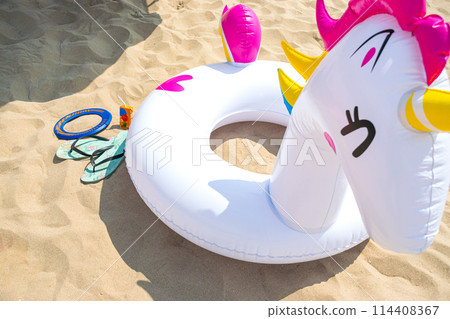 Close up view image of Fun inflatable pony float with flip flops on beach sand Close up view image of Fun inflatable pony float with flip flops on beach sand 114408367