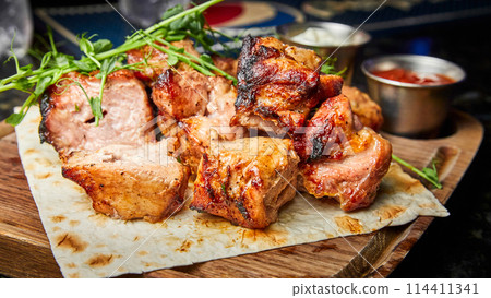 Pork shish kebab on pita bread with two types of sauces Pork shish kebab on pita bread with two types of sauces 114411341