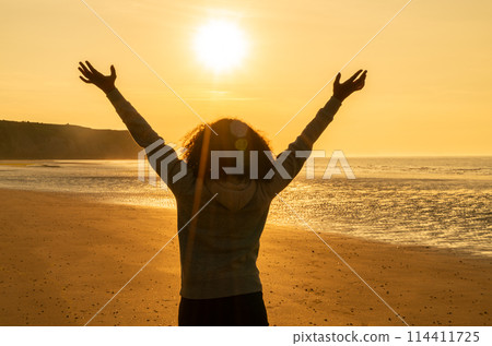 Female Woman Girl Arms Raised on an Empty Beach at Sunset Female Woman Girl Arms Raised on an Empty Beach at Sunset 114411725