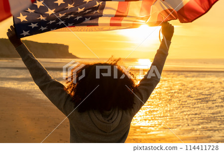 African American Girl Teenager With US Flag Beach at Sunset 114411728