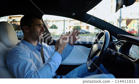 Male businessperson have serious telephone conversation while riding an autonomous self driving electric car. Nervous businessman talks by smartphone during riding on electrical auto with autopilot 114411811