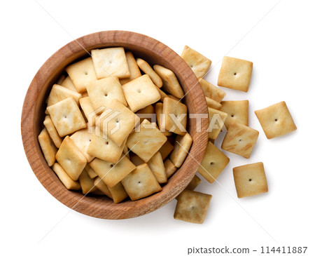 Crackers cookies in a wooden plate and scattered on a white background. Top view 114411887