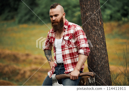 Lumberjack sitting in forest resting after hard work 114411911