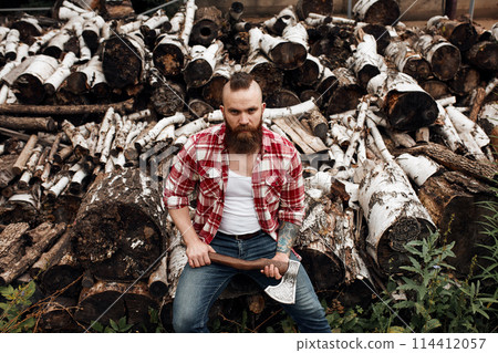 Man sitting on firewoods. Woodcutter with axe resting after work Man sitting on firewoods. Woodcutter with axe resting after work 114412057