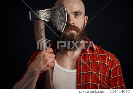 man with mustache is holding a battle axe cover his eye and looking on camera on black background man with mustache is holding a battle axe cover his eye and looking on camera on black background 114414673