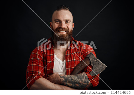 smiling bearded man holding axe looking at camera on black background smiling bearded man holding axe looking at camera on black background 114414695