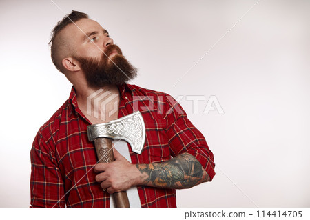 bearded male holding axe on chest and posing in studio 114414705