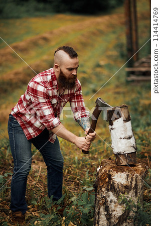 Woodcutter in shirt chopping firewoods, chips fly apart 114414769