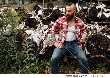 Man sitting on firewoods. Woodcutter with axe resting after work 114414789