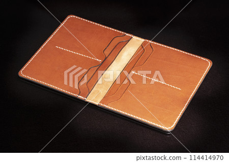 Open leather brown purse with pockets on a dark background. 114414970