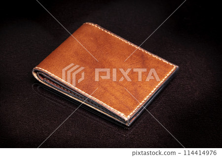 Brown leather wallet on a dark background. Brown leather wallet on a dark background. 114414976