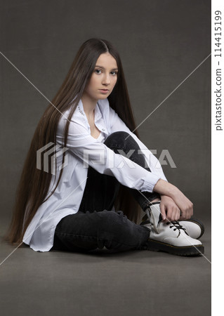 Beautiful brunette girl with very long hair on a gray background. 114415199