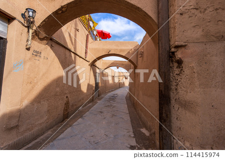 Earthen arches and red parasols in the old town of Yazd. Earthen arches and red parasols in the old town of Yazd. 114415974