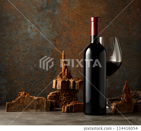 Glass and bottle of red wine with pieces of old wood on a rusty background. Glass and bottle of red wine with pieces of old wood on a rusty background. 114416054