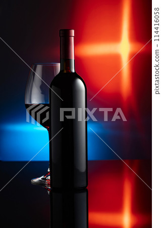 Glass and bottle of red wine on a black reflective background. 114416058