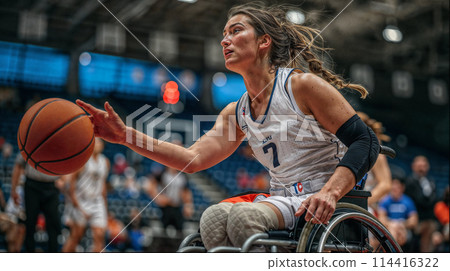 A wheelchair female athlete holding a basketball, showcasing determination and athleticism in sports. 114416322
