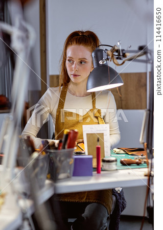 attractive young tailor sews, joins, reinforces, or finishes clothing 114416650