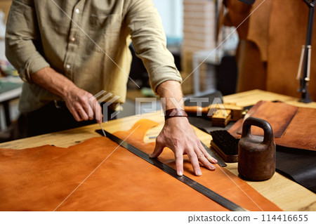 skilled master crafting a new handmade leather wallet in theworkshop. 114416655