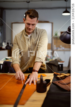 skilled cobbler working with leather in workshop. skilled cobbler working with leather in workshop. 114416716