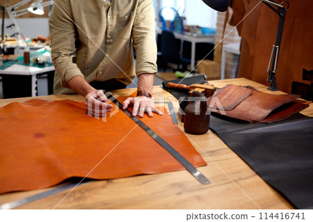 skilled tailor cobbler working with textile in workshop. 114416741