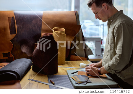 young hardworking artisan using chisel, punching holes young hardworking artisan using chisel, punching holes 114416752