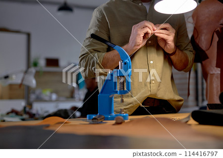 young man makes holes for the belt on a special installation press 114416797