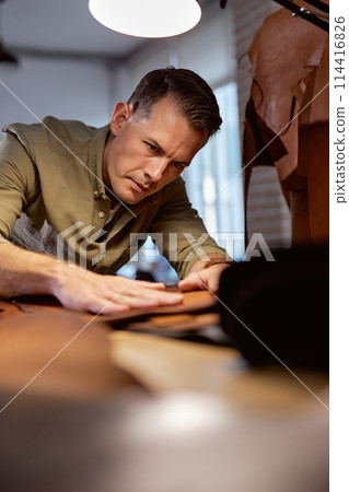 serious man concentrated on selecting leather for sewing bag serious man concentrated on selecting leather for sewing bag 114416826