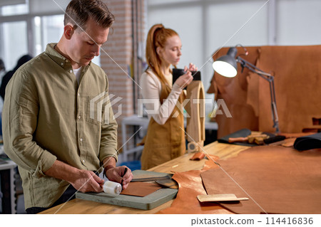 handsome male artsan marks holes in the leather handsome male artsan marks holes in the leather 114416836