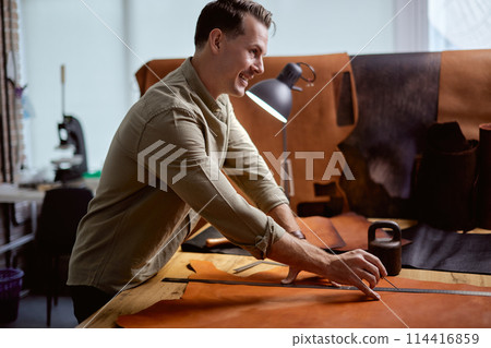 young active man sewing leather goods by hand 114416859