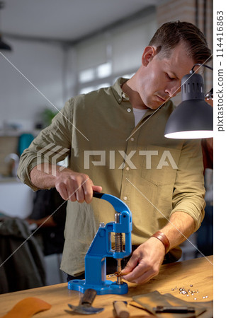 handsome guy in grey shirt pressing, holding the lever on the press machine handsome guy in grey shirt pressing, holding the lever on the press machine 114416863
