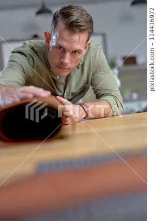 handsome craftsman looking throught the leather roll. 114416972