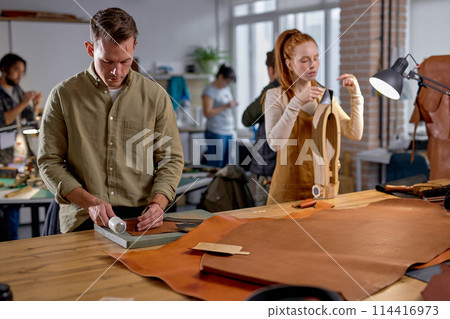 handsome guy punctures holes in leather 114416973