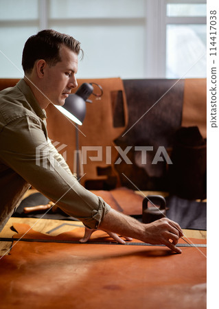 skilled tailor cuts and measures fabric according to a pattern skilled tailor cuts and measures fabric according to a pattern 114417038