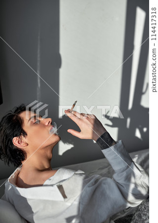 handsome man smoking cannabis weed at home and using his lighter 114417318