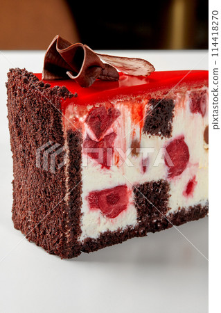 Slice of chocolate cake with sour cream, berries and red icing Slice of chocolate cake with sour cream, berries and red icing 114418270