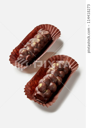 Two dark chocolate bars with hazelnuts in paper wrappers 114418273