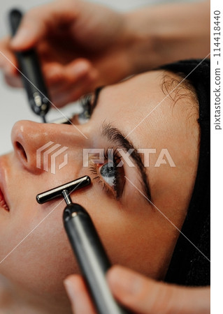 Woman receiving facial massage in beauty salon. 114418440