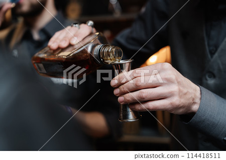 Bartender pours whiskey for tasting. 114418511