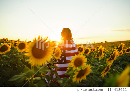 Beautiful girl with the American flag in a sunflower field. 4th of July. Fourth of July. Freedom. Beautiful girl with the American flag in a sunflower field. 4th of July. Fourth of July. Freedom. 114418611